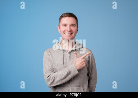 Allegro uomo bello che mostra la direzione di puntamento e con un dito Foto Stock