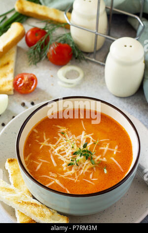 Zuppa di purea di pomodoro con crostini e formaggio in una ciotola su una lavagna luminosa dello sfondo. Il concetto di mangiare sano. Menù dietetici. Foto Stock