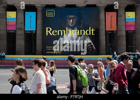 Pedoni su Princes Street a piedi dalla National Gallery of Scotland pubblicità la mostra - Rembrandt, la Gran Bretagna è la scoperta del maestro. Foto Stock