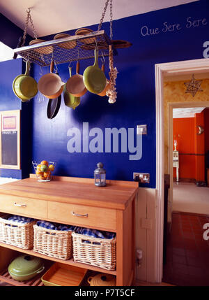 Pentole su rack di stoccaggio sopra credenza in legno con ceste di storage in blu luminoso cucina Foto Stock