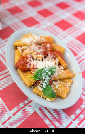 Tradizionale pasta italiana con pomodori, parmigiano e le foglie di basilico servito in un ristorante locale a Napoli, Italia Foto Stock