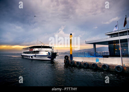 Izmir, Turchia - 28 ottobre 2018. Steamboat sul mare egeo e la baia di Izmir con passeggeri e su NUVOLOSO TRAMONTO. Foto Stock