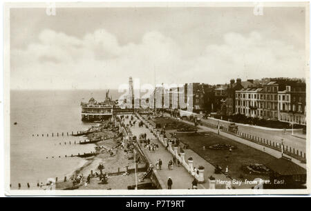 Cartolina datata 1932-1939 mostra una vista di Herne Bay (Kent, Inghilterra) guardando ad est dal terzo Herne Bay Pier. Foto probabilmente preso dalla passeggiata coperta a metà altezza del Grand Pier Pavilion, o eventualmente dal tetto dell'edificio d'ingresso. Questo mostra un aspetto particolare del molo, che era quello di dare una visione insolita della città dal mare, per coloro che non hanno avuto alcun accesso alle navi. Tra il 1932 e il 1939 10 3a Herne Bay Pier 1932-1939 014 Foto Stock