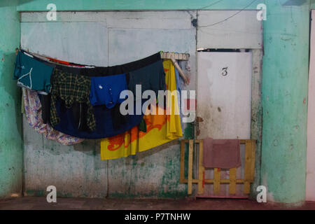 Appartamento numero 3 vestiti e lenzuola appeso ad asciugare in un edificio in rovina. Foto Stock