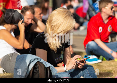 Mosca, Russia - Sabato 7 Luglio, 2018: Fan Fest Mosca, Vorobyovy Gory vicino Università Statale di Mosca. Tifosi guardare i titoli FIFA su schermi di grandi dimensioni qui. Buon umore, bellissimi paesaggi urbani. L'area capacità è più di 30000 persone. Gli appassionati di calcio da parte di molti paesi si incontrano qui. La gente guarda Inghilterra vs Svezia gioco e sono pronte per la Russia vs Croazia gioco. Guardando il gioco online tramite il telefono. Bene, quelle moderne tecnologie. Credito: Alex Immagini/Alamy Live News Foto Stock