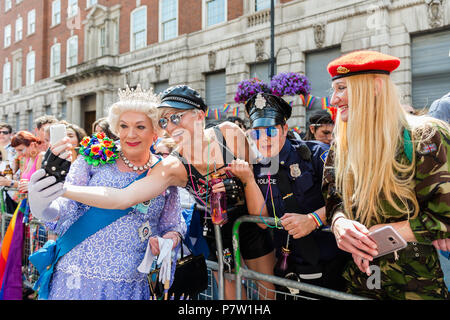 Londra, Regno Unito. 7 Luglio, 2018. Festaioli in abiti miltary prendere un selfie con un partecipante vestita come una regina durante l orgoglio di Londra parade. Il festival annuale attira centinaia di migliaia di persone per le strade della capitale britannica per celebrare il LGBT+ comunità. Credito: Wiktor Szymanowicz/Alamy Live News Foto Stock