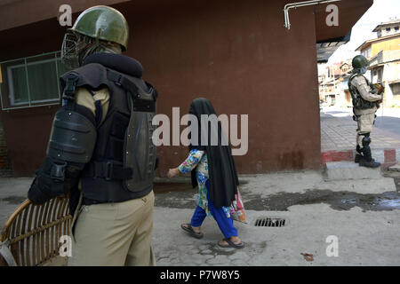 Srinagar, Jammu e Kashmir in India. 8 Luglio, 2018. Il governo indiano le forze si erige come un burqa placcati donna Kashmir passeggiate passato sulle deserte le strade durante un coprifuoco restrizioni, il secondo anniversario della morte di Burhan Muzaffar Wani un giovane comandante ribelle a Srinagar, la capitale estiva di Indiano Kashmir amministrato, India. Le autorità indiane implementato gran numero sul loro le forze governative in Kashmir attraverso la maggior parte di Indiano-Kashmir amministrato per contrastare anti indiano dimostrazioni di protesta dei musulmani del Kashmir su il secondo anniversario della morte di Burhan Muzaffar wani, un giovane ribelle com Foto Stock