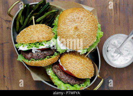 Hamburger con costolette di manzo fritte e Fagioli baccelli sono serviti in una padella sul tavolo di legno con salsa, vista dall'alto Foto Stock