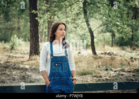 Bella giovane donna in tuta in jeans all'esterno. Foto Stock