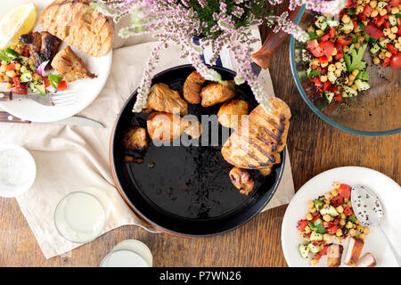 Pezzi fritti in padella sul tavolo di legno con verdura fresca insalata di quinoa nero e i ceci e bicchiere di limonata, vista dall'alto. Cena gustosa tabella conce Foto Stock