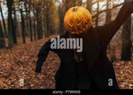 Ritratto di un pauroso Jack-lanterna con una zucca sulla sua testa. La leggenda di Halloween. Vestito di nero cappotto. Foresta di autunno Foto Stock