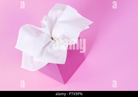 Lo stile di Kleenex tessuti nella casella vuota isolata su un morbido sfondo rosa. Foto Stock
