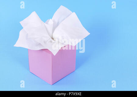 Lo stile di Kleenex tessuti nel bianco del riquadro rosa isolata su uno sfondo blu. Foto Stock