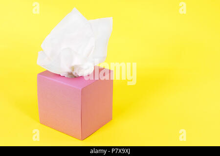 Tessuti in bianco scatola rosa isolata su uno sfondo giallo. Foto Stock