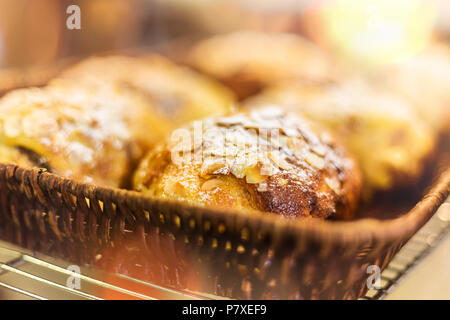Mandorle francese croissant al cioccolato in bambù cesto tessuto, messa a fuoco selettiva e lens flare Foto Stock