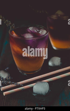 Peach aperol spritz con fette di pesche e l'acqua di lavanda sulla scrivania in legno. Foto Stock