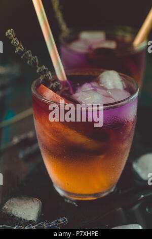 Peach aperol spritz con fette di pesche e l'acqua di lavanda sulla scrivania in legno. Foto Stock