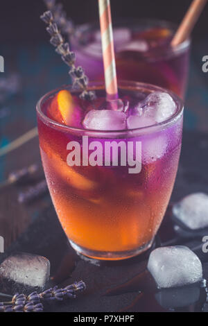 Peach aperol spritz con fette di pesche e l'acqua di lavanda sulla scrivania in legno. Foto Stock