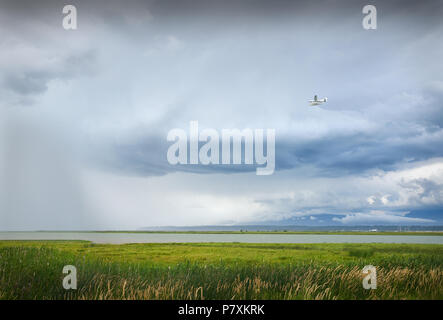 Un piano di mosche in nubi e pioggia sopra il fiume Fraser e l'Aeroporto di Vancouver. Foto Stock