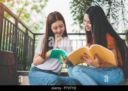 Due Asian bellezza delle ragazze e la lettura di libri di tutoraggio per esame finale insieme. Studente sorridente e seduta sulla scala. Istruzione e il ritorno a scuola c Foto Stock