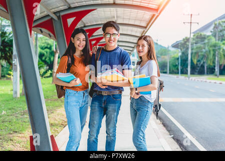 Tre asiatici giovani studenti del campus godetevi il tutoraggio e la lettura di libri insieme. L'amicizia e il concetto di istruzione. Il campus della scuola e università del tema. Hap Foto Stock