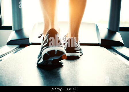 In prossimità di persone che esercitano sul tapis roulant. Close-up di donna gambe camminando dal tapis roulant in sports club. Fitness e Body costruire concetto. Allenamento Foto Stock