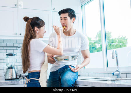 Donna di alimentazione per alimentare l'uomo come amanti o coppie in camera con cucina. Luna di miele e il concetto di matrimonio. Tema di cottura Foto Stock