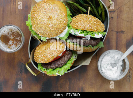 Vista superiore hamburger con costolette di manzo fritte e Fagioli baccelli sono serviti in una padella sul tavolo di legno con birra e salsa, vista dall'alto Foto Stock