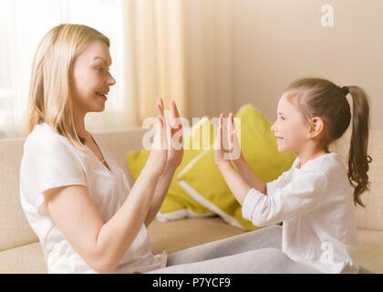 Carino bambina e la sua bella madre sono la riproduzione di giochi a casa, battendo le mani insieme. Foto Stock