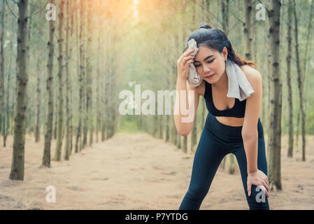 Asian bellezza donna tergi sudore nella foresta. Asciugamano e elementi di sudore. Sport e un sano concetto. Jogging ed esecuzione di concetto. Rilassarsi e prendere un brea Foto Stock