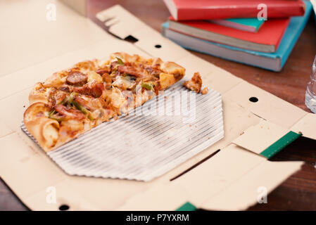 Pezzi di pizza sul tavolo. La Pizza sul tavolo con libri e bevande per gli studenti che desiderano celebrare la festa dopo l'esame. Tagliare la pizza in scatola di consegna. Foo Foto Stock
