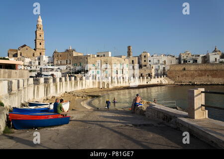 MONOPOLI, Italia - 2 Luglio 2018: persone nuotare sulla spiaggia Porta Vecchia vicino alla cattedrale durante il Sunrise il 2 luglio 2018 a Monopoli, Italia. Foto Stock