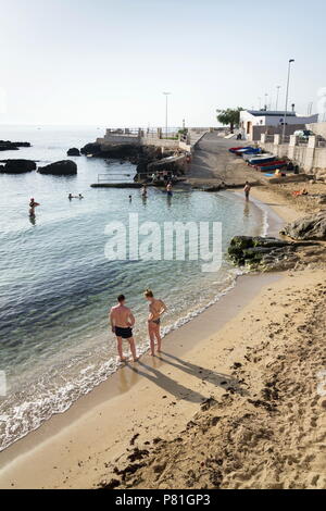 MONOPOLI, Italia - 2 Luglio 2018: persone nuotare sulla spiaggia Porta Vecchia vicino alla cattedrale durante il Sunrise il 2 luglio 2018 a Monopoli, Italia. Foto Stock