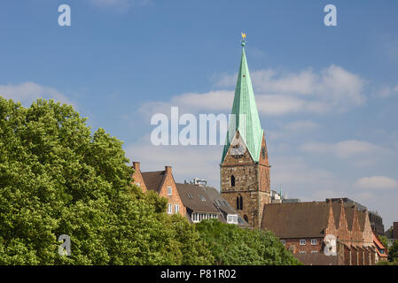 La Chiesa di San Martino, Brema, Germania vista dal fiume Weser con lussureggiante fogliame verde in primo piano Foto Stock