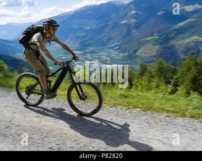 Biker casual con e-bike attraverso le Alpi Italiane Foto Stock