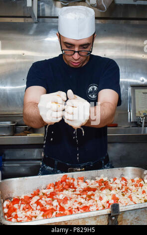 La base navale di KITSAP-BREMERTON, nello Stato di Washington (10 maggio 2016) - Specialista culinari marinaio Jared Brenemanpaffumi, nativo di sant'Agostino, Fla., spreme limoni sopra le cipolle e i pomodori per fare la salsa a bordo USS Nimitz CVN (68) in preparazione per il prossimo pasto. Nimitz è attualmente sottoposto ad un esteso pianificata la manutenzione incrementale disponibilità a Puget Sound Naval Shipyard e Manutenzione intermedia la struttura in cui la nave sta ricevendo una manutenzione pianificata e aggiornamenti. Foto Stock