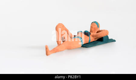 Lady in miniatura in un bikini sdraiato a prendere il sole godendo le vacanze estive isolato su bianco con spazio di copia Foto Stock