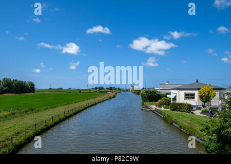 Tipica polder olandesi con canal polder e polder mill all'orizzonte. Foto Stock