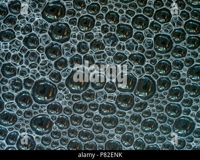 Un primo piano di uno strato di lotti di piccole bolle di sapone galleggiante sull'acqua Foto Stock