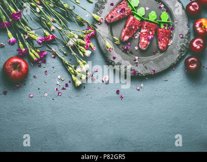 In casa Red Frutte gelato o ghiaccioli nella piastra sul tavolo da cucina sfondo con fiori da giardino e gli ingredienti, vista dall'alto. Stagionale organico sani Foto Stock