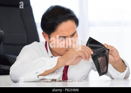 Un fallimento, ha rotto e frustrato uomo sta avendo problemi finanziari con le monete lasciate sul tavolo e un portafoglio vuoto. Foto Stock