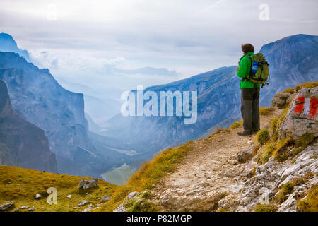 Giovane avventuriero in piedi su una scogliera in Dolomiti, Italia Foto Stock