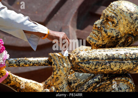 Mano di persone gild alla statua del Buddha oro ricoperta con un sottile strato di oro. Foto Stock