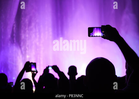 La gente scatta foto o video di un concerto o spettacolo di illuminazione sugli smartphone. Sochi Foto Stock