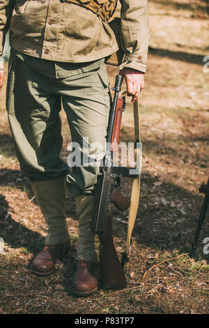 Ri-enactor vestito come Soldato di fanteria Usa della II Guerra Mondiale mantiene i moschetti mitragliatori arma nelle mani. Foto Stock