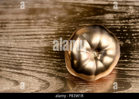 Oro dipinto di pomodoro su golden e sfondo di legno. Foto Stock