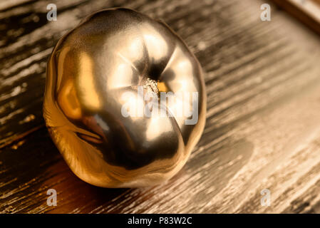 Oro dipinto di pomodoro su golden e sfondo di legno. Foto Stock