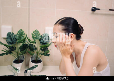 Donna felice deterge la pelle con la schiuma in bagno. Foto Stock