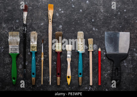 Set di vecchio grungy pennelli per dipingere sulla trama astratta sfondo grigio scuro con macchie. Vista dall'alto, il concetto di riparazione. Foto Stock