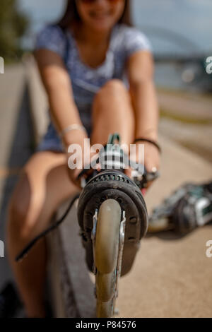 Close-up di una giovane donna di preparare per la pratica del pattinaggio a rotelle. Foto Stock